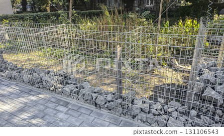 Stone fence construction. Mesh base with stones inside. Open space design 131106543