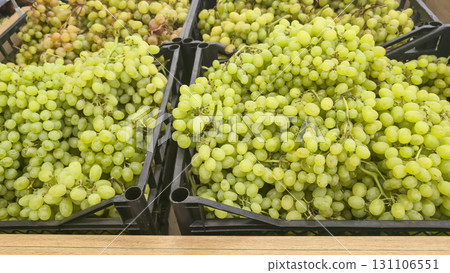 Green grapes in large boxes on store shelves. Fruit display and sale. Green grapes in large boxes on store shelves. Fruit display and sale. 131106551