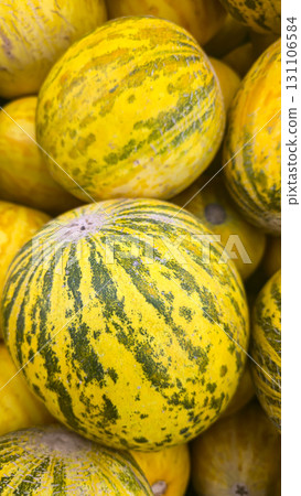 Round yellow melons in large crates on store shelves. Fruit display and sale. 131106584