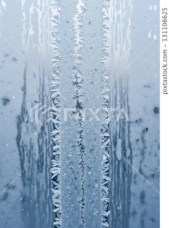 Frozen Glass Window with Delicate Frost Patterns and Blue Tint Background Closeup Frozen Glass Window with Delicate Frost Patterns and Blue Tint Background Closeup 131106625