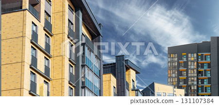 Residential complex in cityscape. Modern yellow and gray brick building with panel facade, balconies 131107384
