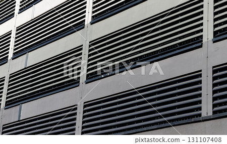 Ventilation facade closeup. Modern building exterior with metal louver system, grid pattern, airflow Ventilation facade closeup. Modern building exterior with metal louver system, grid pattern, airflow 131107408