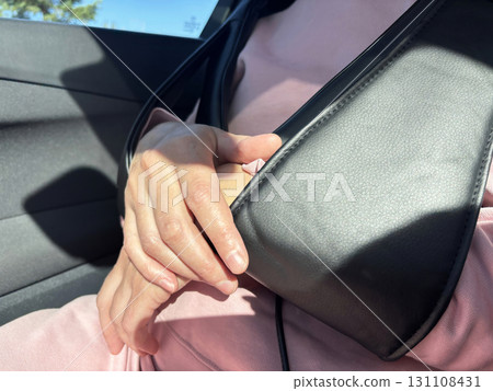 A woman enjoys a massage with an electric massager in a car. Relaxation during a long drive or trip, portable massage device for neck and shoulders, health and wellness lifestyle 131108431