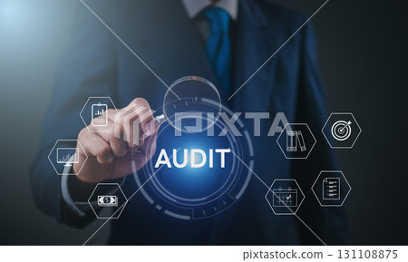 Businessman performing financial audit with magnifying glass on digital dashboard using virtual interface, showcasing data analysis, compliance, and corporate risk management. 131108875
