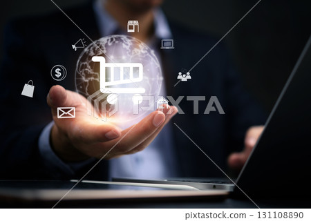 Businessperson holding a glowing globe with various e-commerce symbols like a shopping cart, house, and laptop. Ideal for representing global online shopping and digital transactions. 131108890