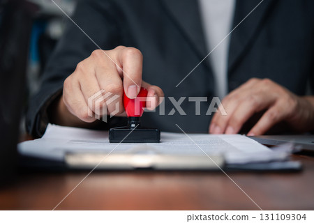 Businessman stamping document to approve official contract, concept of legal authorization and business validation. financial, banking, or investment documents at his desk official paperwork. Businessman stamping document to approve official contract, concept of legal authorization and business validation. financial, banking, or investment documents at his desk official paperwork. 131109304