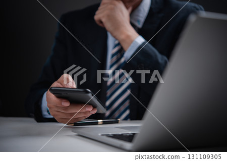 Corporate leader holding phone with pen and laptop, great for concepts of business thinking, fintech, and remote leadership. Corporate leader holding phone with pen and laptop, great for concepts of business thinking, fintech, and remote leadership. 131109305