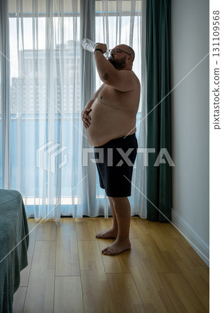 Fat man suffers dying from heat. Guy replenishes water balance suffers from dehydration, summer heat Fat man suffers dying from heat. Guy replenishes water balance suffers from dehydration, summer heat 131109568