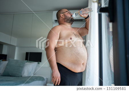 Fat man suffers dying from heat. Guy drinks lot water trying to cope with abnormal summer warmth Fat man suffers dying from heat. Guy drinks lot water trying to cope with abnormal summer warmth 131109581