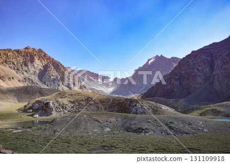 Idyllic summer landscape with hiking trail in the mountains with beautiful fresh green mountain pastures and snow-capped mountain tops in the background, National park. Idyllic summer landscape with hiking trail in the mountains with beautiful fresh green mountain pastures and snow-capped mountain tops in the background, National park. 131109918