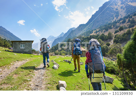 Idyllic summer landscape with hiking people in the mountains with beautiful fresh green mountain pastures and forest. Alai ridge mountains, Kyrgyzstan Idyllic summer landscape with hiking people in the mountains with beautiful fresh green mountain pastures and forest. Alai ridge mountains, Kyrgyzstan 131109930