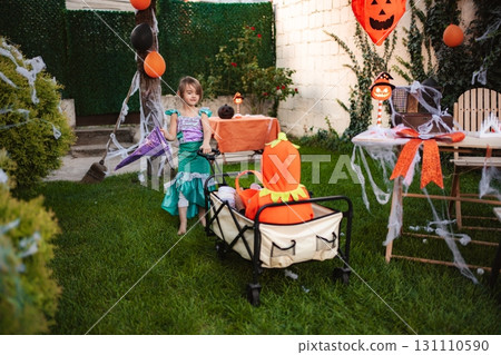 Children celebrating Halloween pulling wagon in decorated backyard Children celebrating Halloween pulling wagon in decorated backyard 131110590