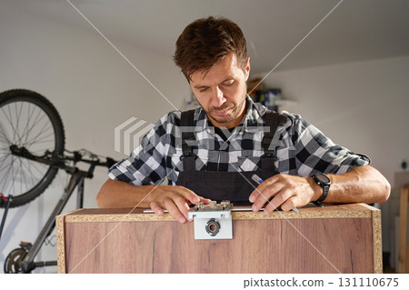 Carpenter using drilling jig tool to assemble wooden furniture 131110675