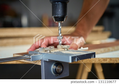 Carpenter drilling wooden panel using jig tool for precise holes Carpenter drilling wooden panel using jig tool for precise holes 131110677