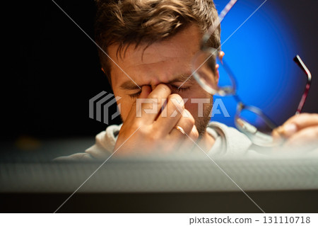 Tired man rubbing eyes while holding glasses 131110718