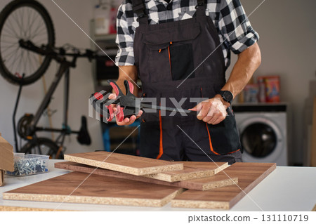 Carpenter preparing wooden boards with clamp tool in workshop 131110719