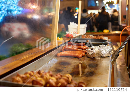 Grilled sausages and baked potatoes on street food stall at Christmas market 131110734