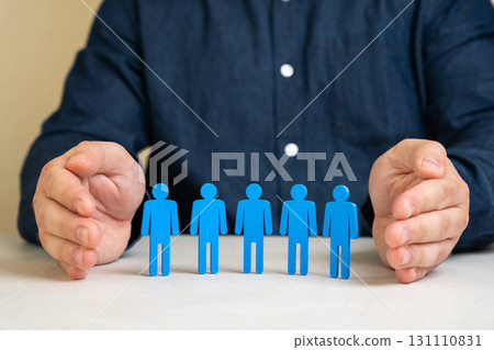 Businessman shields his team with a protective gesture. Symbolizing employee care, life insurance, workplace security and social protection within the company. Safety and human resources. 131110831