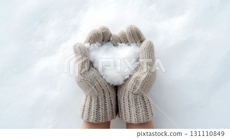 Hands in woolen gloves holding heart-shaped snow on a soft snowy background 131110849