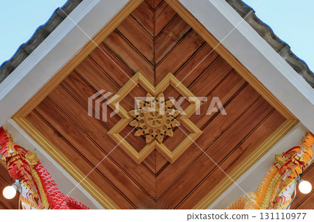 Wooden ceiling with intricate golden floral carvings and symmetrical geometric frames Wooden ceiling with intricate golden floral carvings and symmetrical geometric frames 131110977