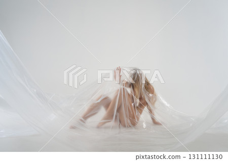 Blonde woman in a studio wrapped in plastic for a beauty session 131111130