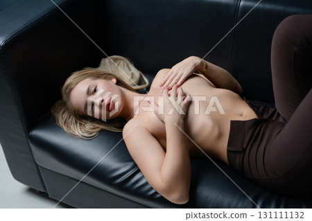 Portrait of a beautiful blonde woman posing in a studio setting on a couch Portrait of a beautiful blonde woman posing in a studio setting on a couch 131111132