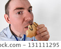 Office worker, man eating a cookie. Close-up wide-angle facial portrait 131111295