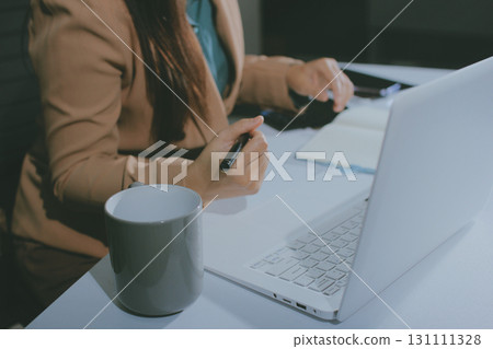 Close-up of businessman's hands making notes, mobiles, chart, desk, office 131111328