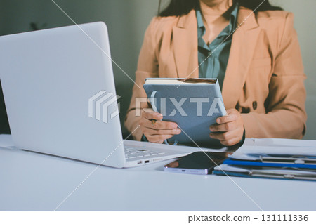 Close-up of businessman's hands making notes, mobiles, chart, desk, office 131111336
