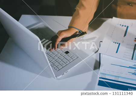 Close-up of businessman's hands making notes, mobiles, chart, desk, office Close-up of businessman's hands making notes, mobiles, chart, desk, office 131111340