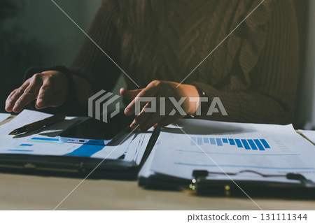 Close-up of businessman's hands making notes, mobiles, chart, desk, office Close-up of businessman's hands making notes, mobiles, chart, desk, office 131111344