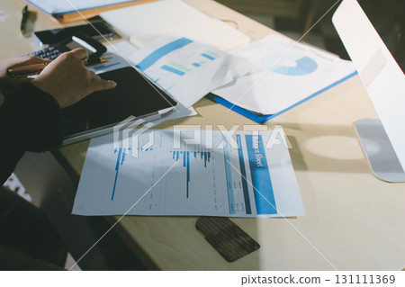 Close-up of businessman's hands making notes, mobiles, chart, desk, office 131111369