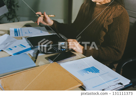Close-up of businessman's hands making notes, mobiles, chart, desk, office Close-up of businessman's hands making notes, mobiles, chart, desk, office 131111373