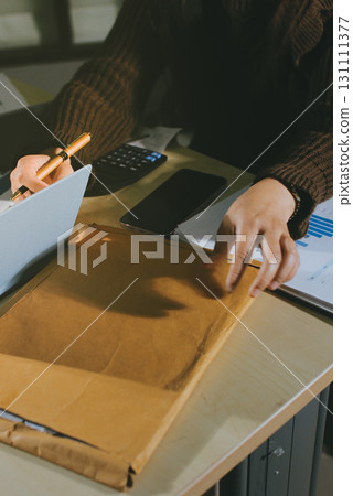 Close-up of businessman's hands making notes, mobiles, chart, desk, office Close-up of businessman's hands making notes, mobiles, chart, desk, office 131111377