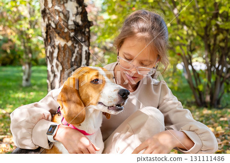 Young girl playing with her dog in the park during autumn. Joyful moments of pet ownership. Young girl playing with her dog in the park during autumn. Joyful moments of pet ownership. 131111486