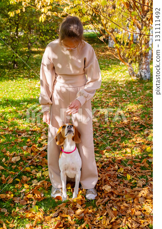 Girl with dog in autumn park. Fall season leisure with pet. 131111492