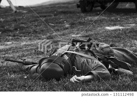 Re-enactor Dressed As German Wehrmacht Soldier Lies Slain In Reconstruction Of Battles World War Ii. German Infantry Soldier In World War Ii. Reconstruction. Black And White Video Re-enactor Dressed As German Wehrmacht Soldier Lies Slain In Reconstruction Of Battles World War Ii. German Infantry Soldier In World War Ii. Reconstruction. Black And White Video 131112498