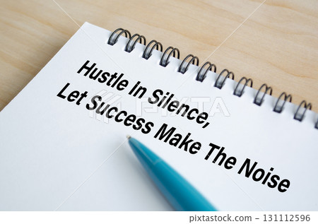 Hustle Until You Make It Happen text written on a spiral notepad with motivational handwriting in blue pen. 131112596