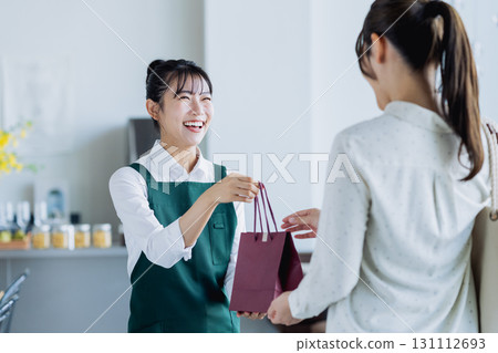 A young female staff member handing over items at a cafe A young female staff member handing over items at a cafe 131112693