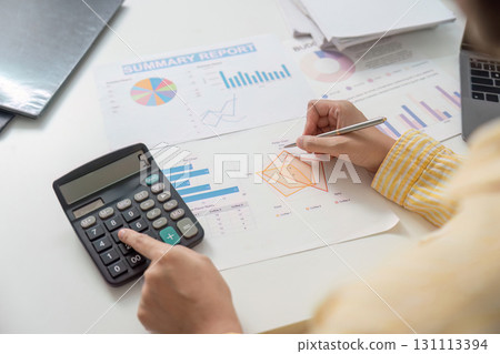 Data Management. Professional using calculator and pen for report analysis. 131113394