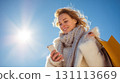 Young Woman Smiling While Christmas Shopping and Gazing at Phone 131113669