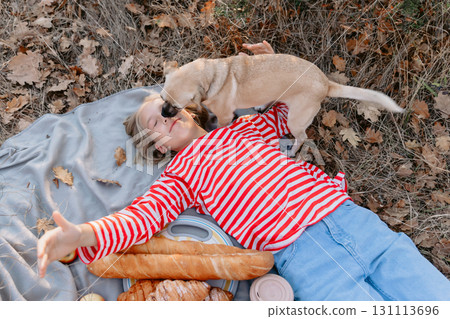 Young teenage girl lies on a plaid with friendly dog Young teenage girl lies on a plaid with friendly dog 131113696