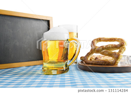 Blackboard with beer mugs and a pretzel loaf with a blue checkered tablecloth or napkin on a white table. Copy space. Concept of Oktoberfest. Bavarian German culture festival decoration symbol Blackboard with beer mugs and a pretzel loaf with a blue checkered tablecloth or napkin on a white table. Copy space. Concept of Oktoberfest. Bavarian German culture festival decoration symbol 131114284