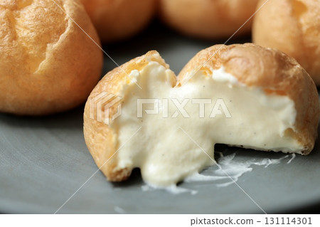 A cross section of a petit cream puff with a soft skin and plenty of cream 131114301