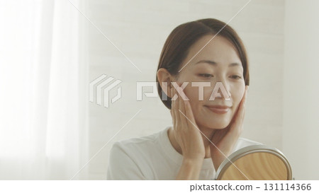 A Japanese woman in her 40s checking her skin condition in the mirror A Japanese woman in her 40s checking her skin condition in the mirror 131114366