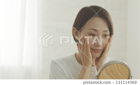 一位 40 多歲的日本女性對著鏡子檢查自己的皮膚狀況 一位 40 多歲的日本女性對著鏡子檢查自己的皮膚狀況 131114369
