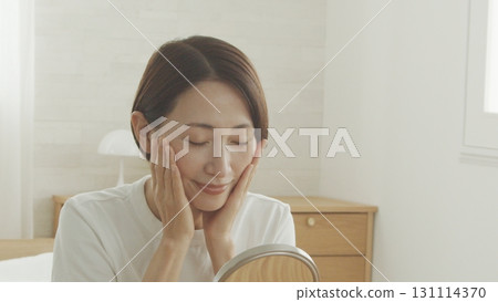 一位 40 多歲的日本女性對著鏡子檢查自己的皮膚狀況 一位 40 多歲的日本女性對著鏡子檢查自己的皮膚狀況 131114370