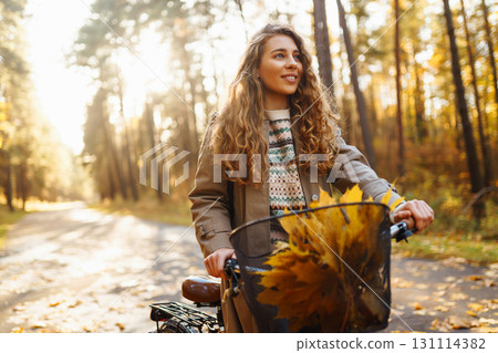 Beautiful woman in stylish clothes with bicycle walking in autumn park Woman walking in sunny forest 131114382