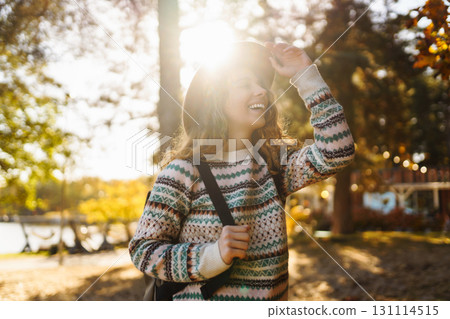 Sunny lifestyle portrait of young stylish woman walking on park, wearing cute trendy hat. Relaxation 131114515