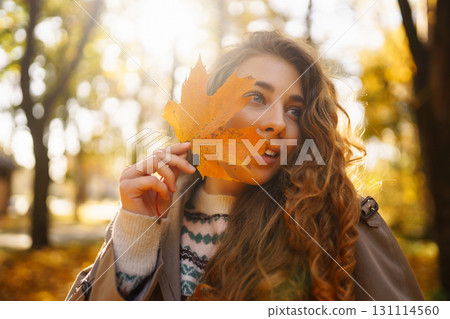 Happy woman enjoying autumn weather in the sunny park. Enjoying nature. Fashion, style concept. Happy woman enjoying autumn weather in the sunny park. Enjoying nature. Fashion, style concept. 131114560